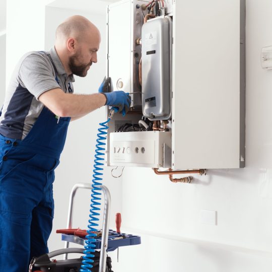 Gas engineer checking and cleaning a boiler during the inspection at home